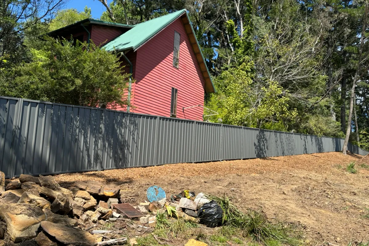 Monument Colorbond boundary fence on sloped embankment